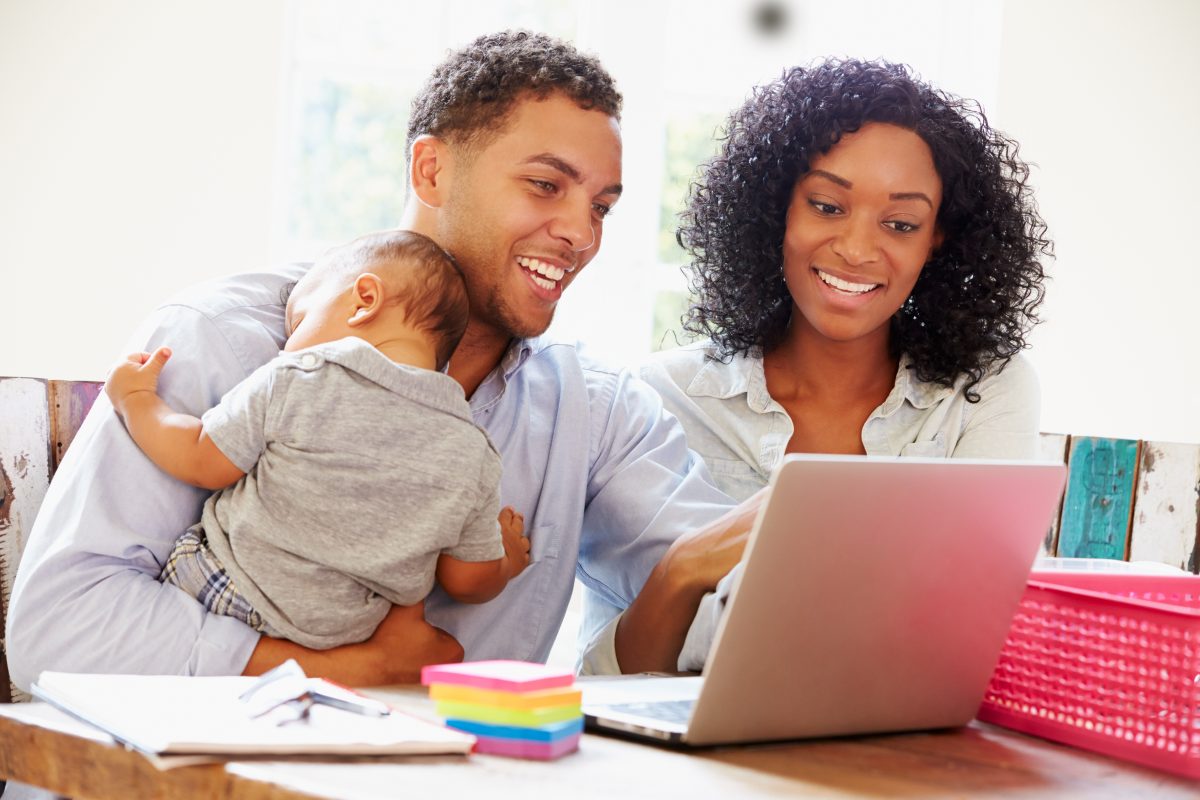 Young working professional couple with baby smiling over a laptop. Professional Executive Associates In. home admin help